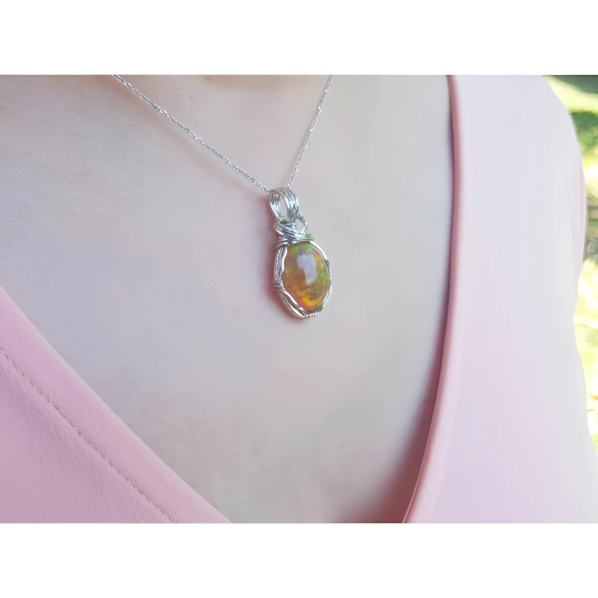 Ethiopian opal pendant with vibrant play of colors and brown pinpoint fire in a silver wire wrap.