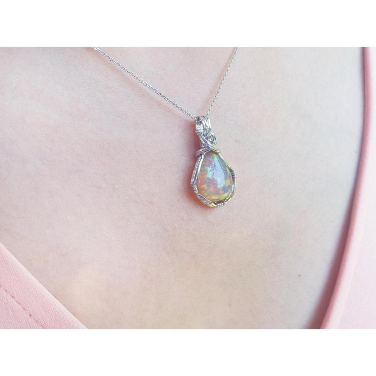 Welo Ethiopian multicolor opal pendant with silver wire wrap, worn on a pink top.