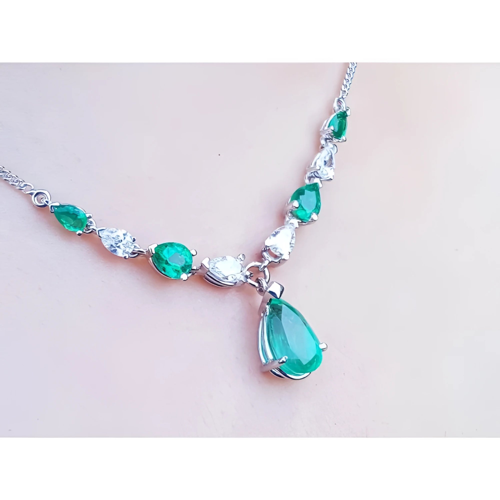14k white gold necklace with pear-shaped emeralds and diamonds, featuring a large emerald drop pendant.