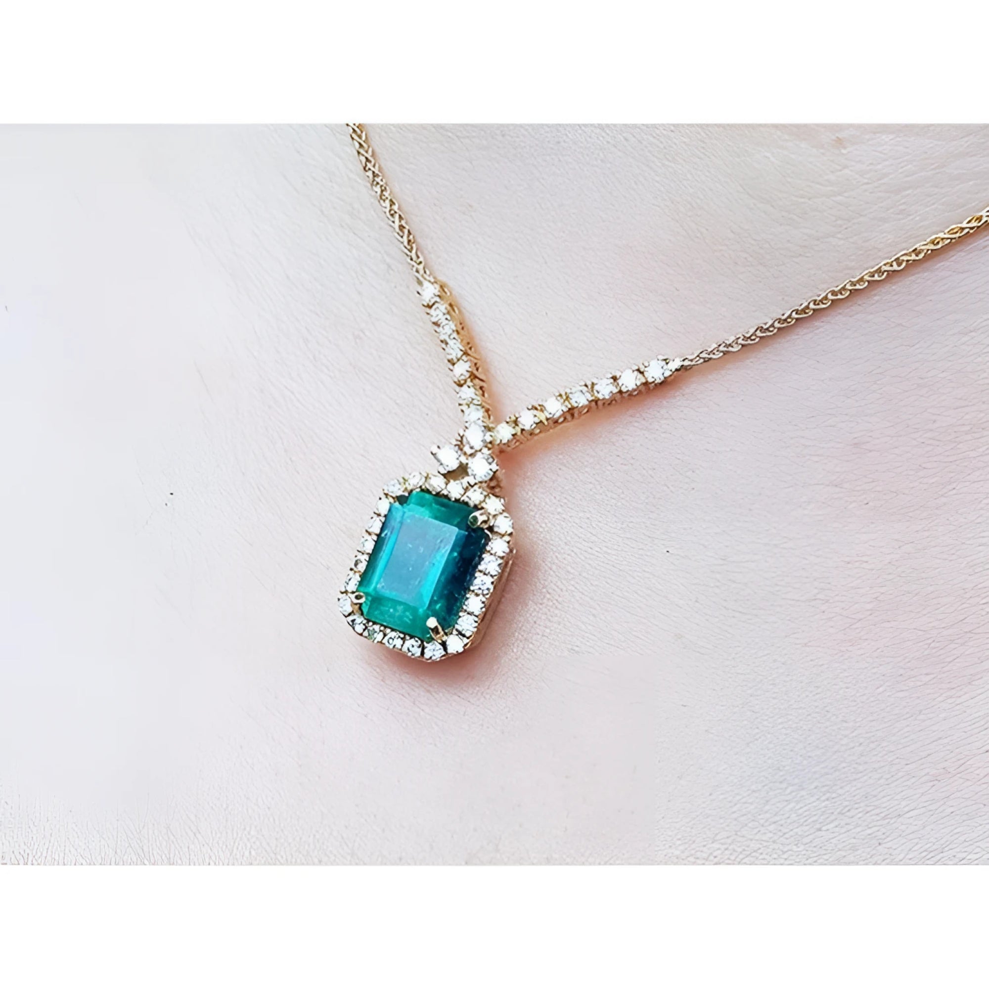 14K yellow gold halo necklace with a rectangular bluish-deep green emerald and natural diamonds.