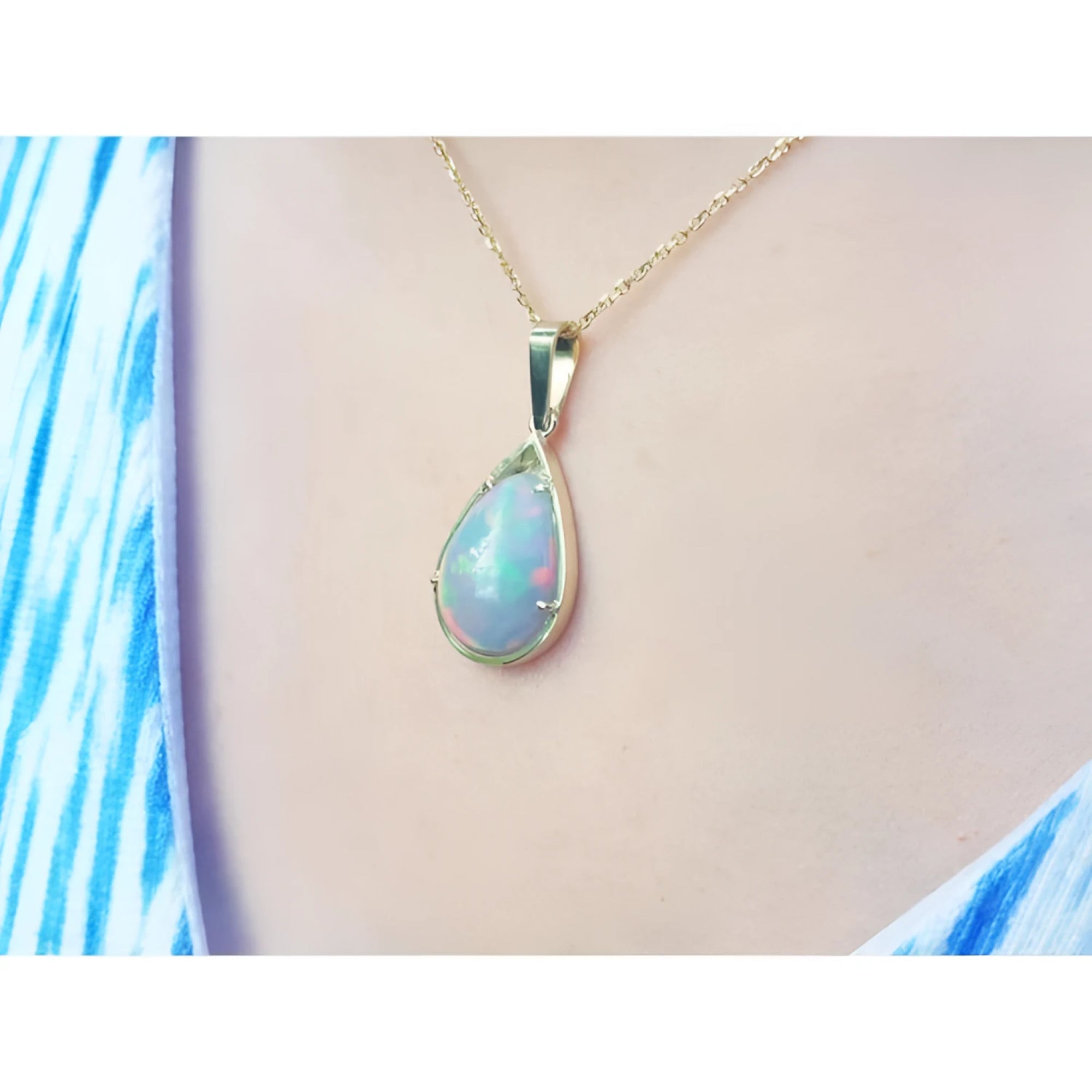 Pear-shaped Ethiopian Welo opal pendant in 14K yellow gold, showing fire red-orange and rainbow colors.