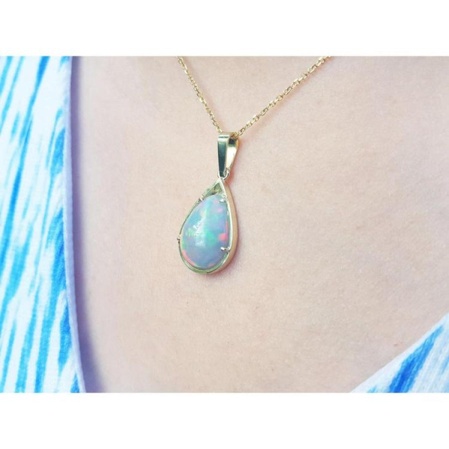 Pear-shaped Ethiopian Welo opal pendant in 14K yellow gold, showing fire red-orange and rainbow colors.