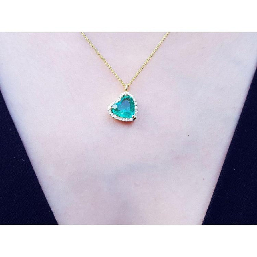 Tilted heart emerald necklace with halo diamonds on an 18K yellow gold chain.