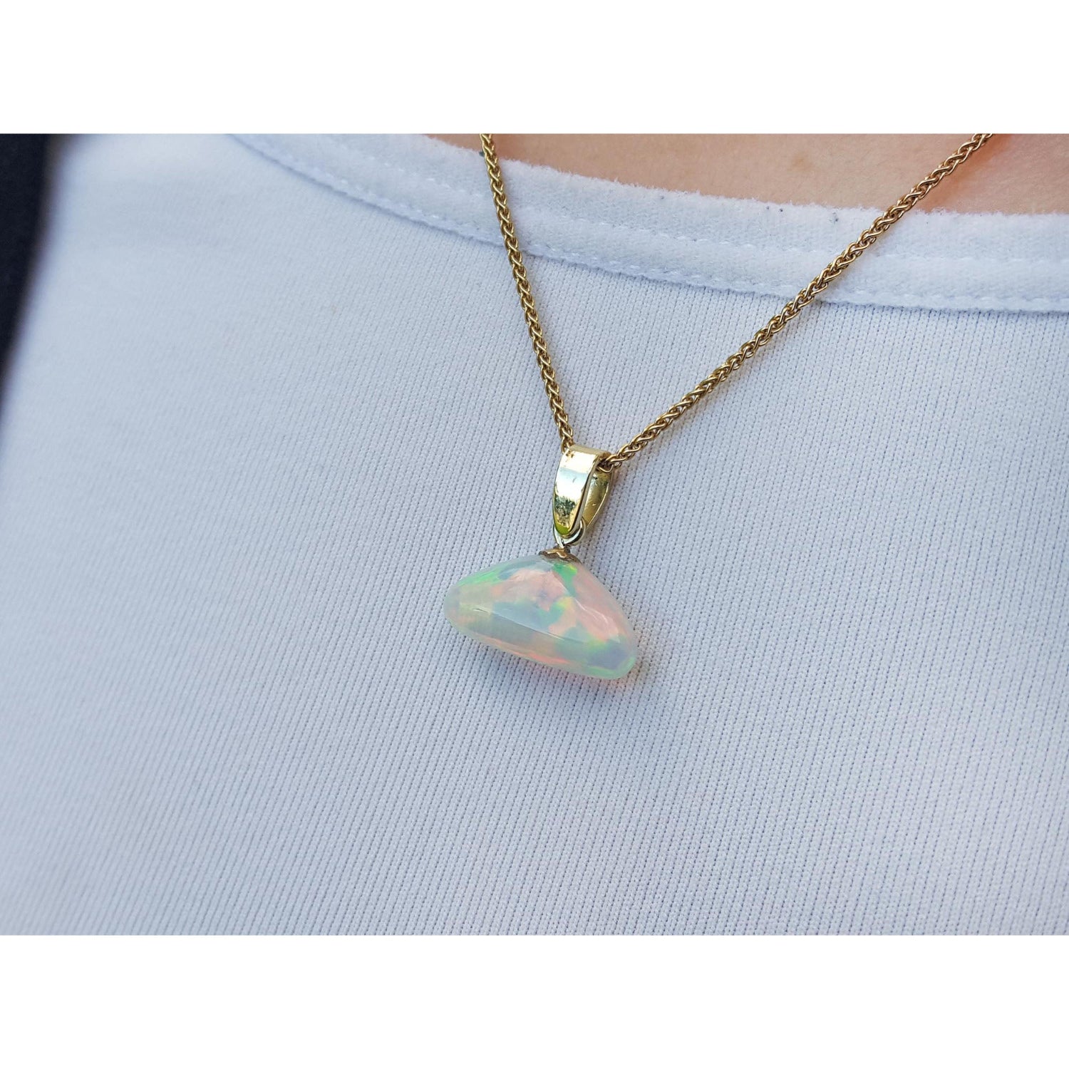 Necklace with an opal pendant on a person&#39;s neck and light blue background.