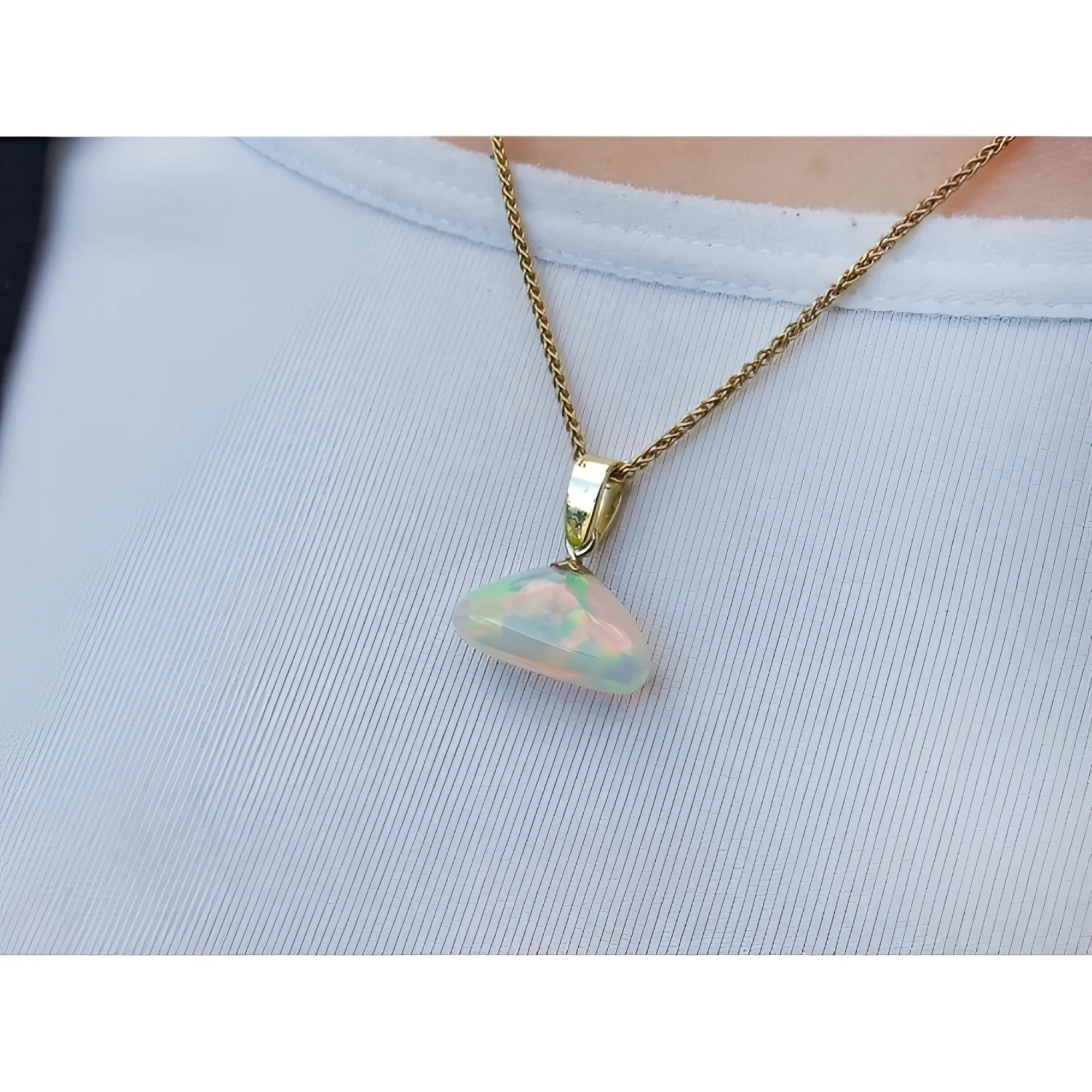 Ethiopian Welo opal pendant with full play of colors, dangling from a 14k gold bail on a chain.