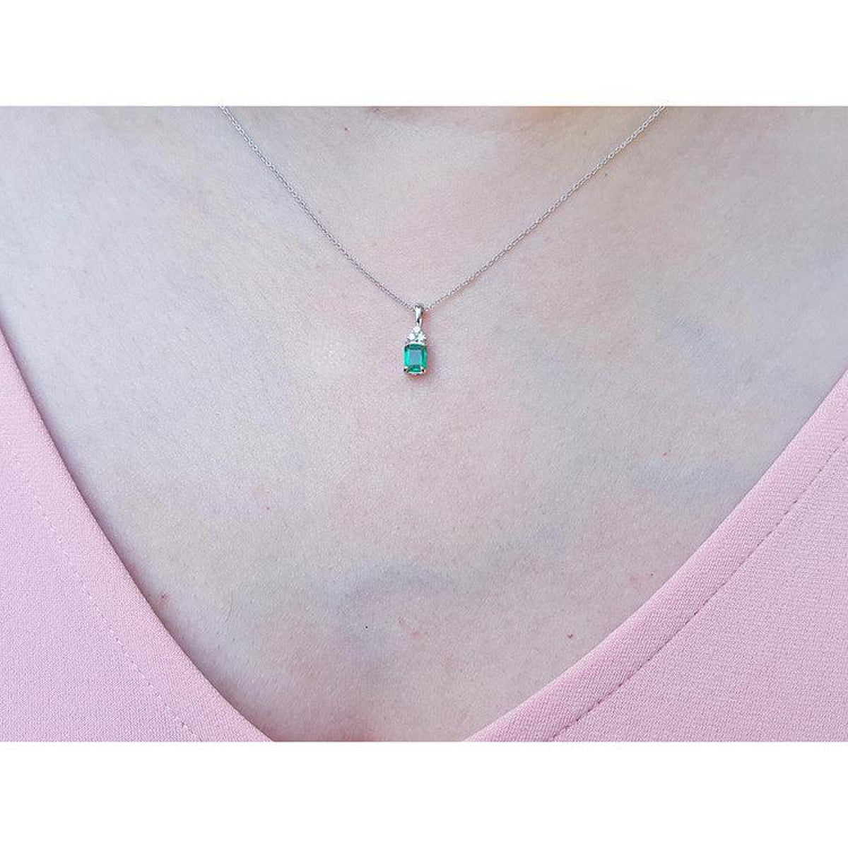 0.27 ct emerald necklace pendant in 14K white gold, worn on a woman's chest.