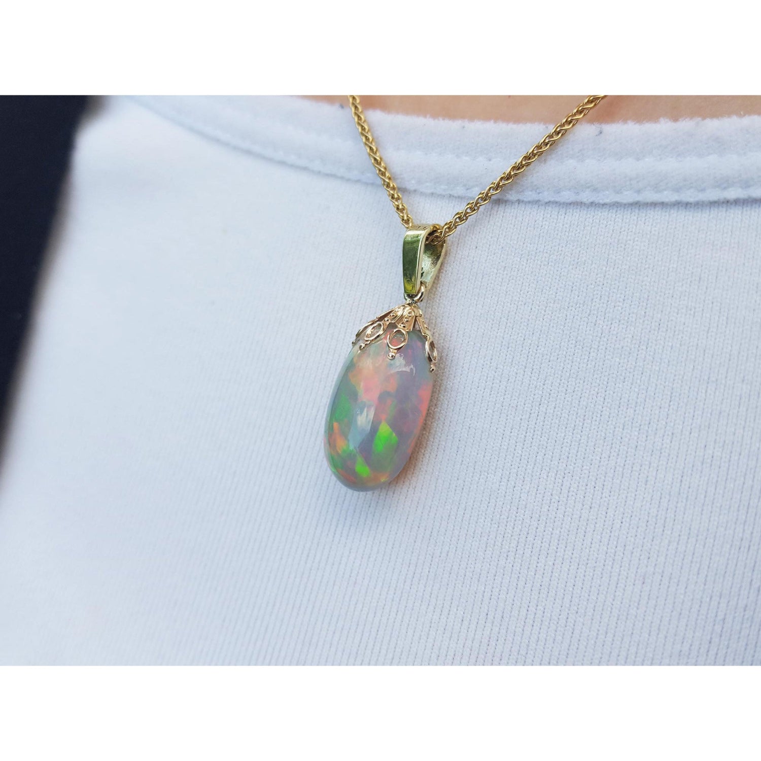 Opal pendant on a gold chain against a light blue background