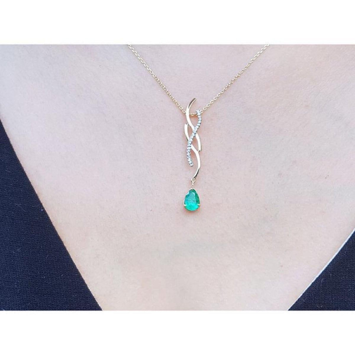Pear-shaped emerald pendant on a twisted 14K yellow gold slider necklace with diamond accents.