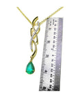 14K yellow gold twisted slider necklace with a pear-shaped emerald pendant and diamond accents, shown with a ruler.