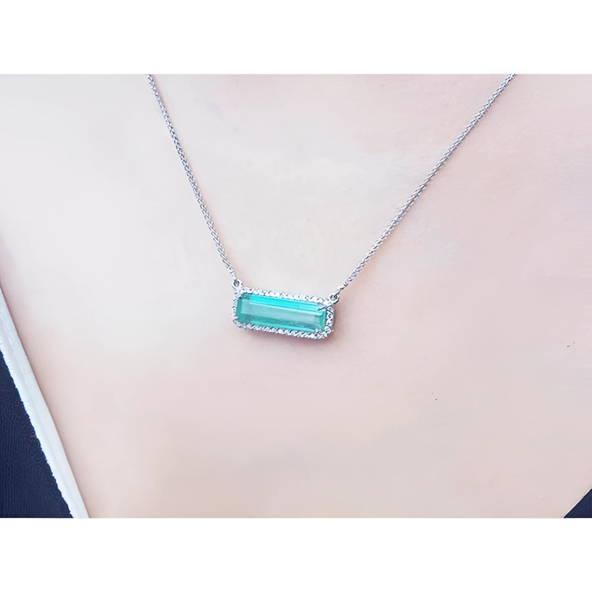 18K white gold necklace with a rectangular emerald-cut Colombian emerald and diamond halo, East-West design.