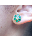 Close-up of an ear wearing a floral emerald and diamond earring.