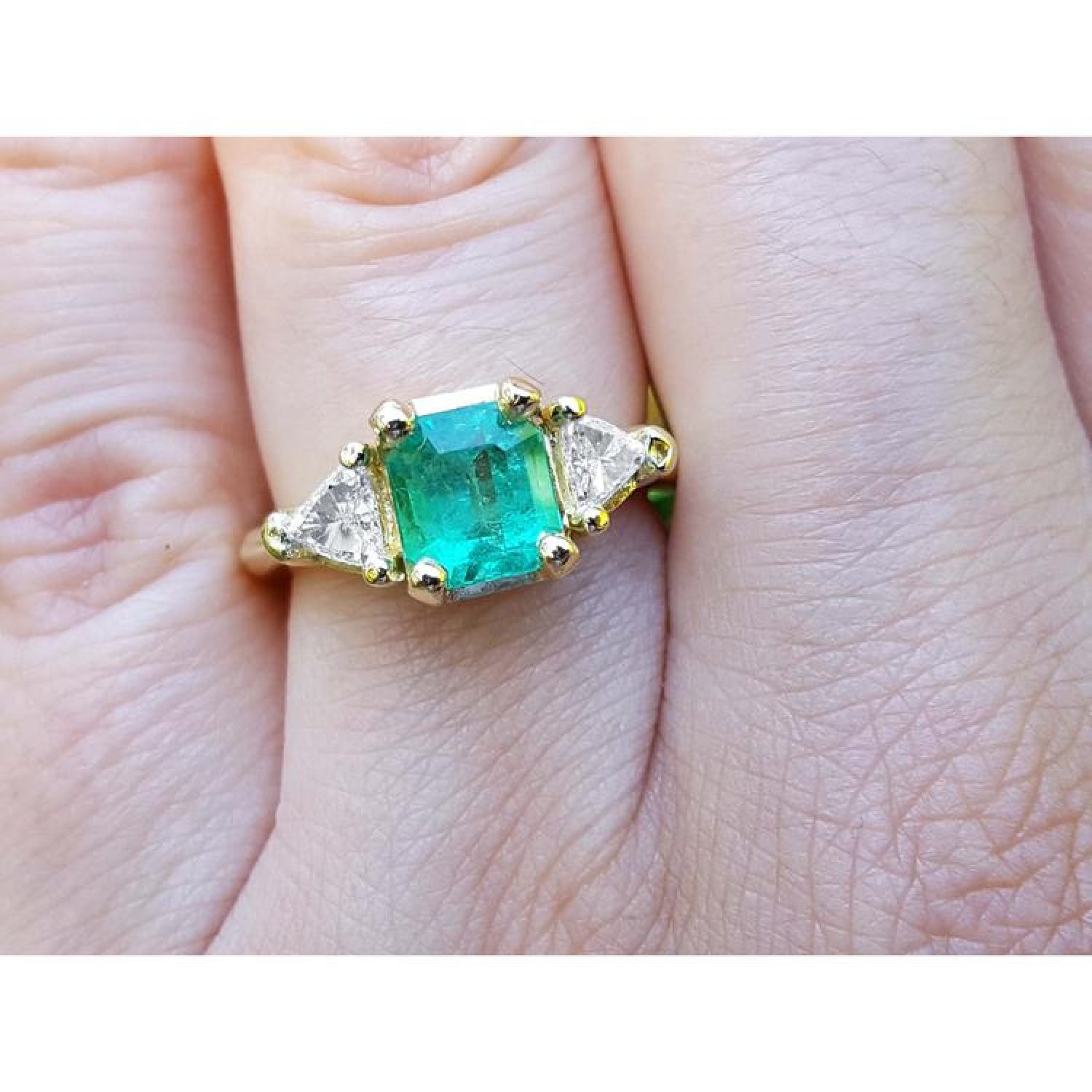 1.27 ct natural Colombian emerald three-stone ring with trillion diamonds in 18K yellow gold.