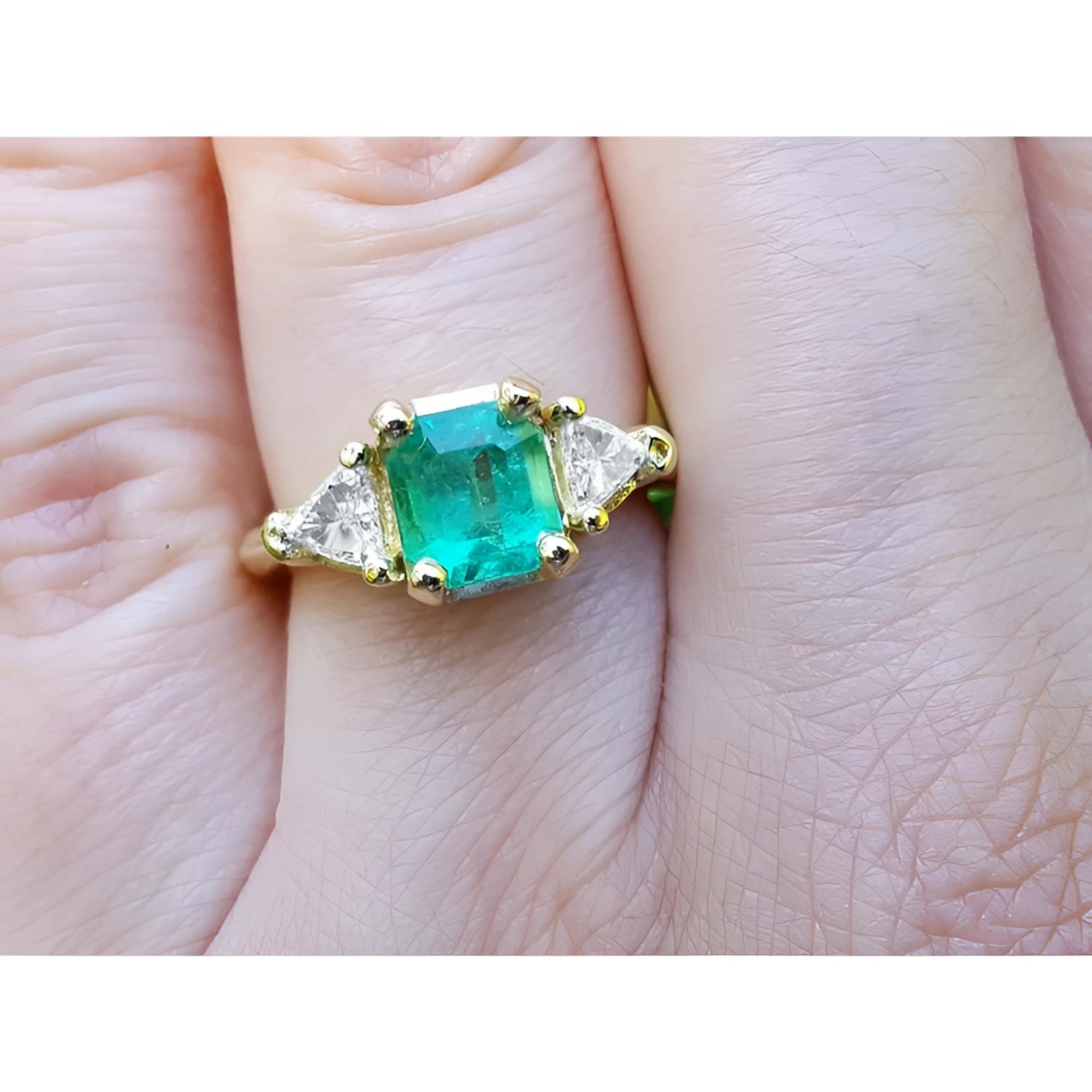 1.27 ct natural Colombian emerald three-stone ring with trillion diamonds in 18K yellow gold.