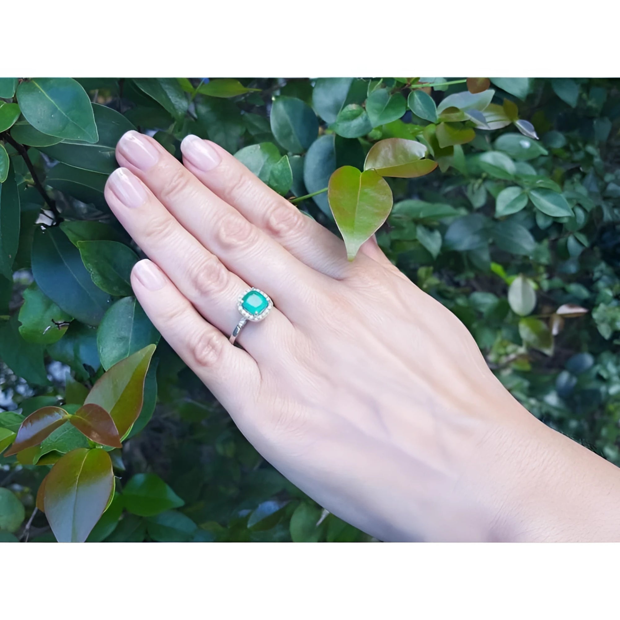 1.71 ct. Colombian emerald cushion-cut halo diamond ring in 14K white gold on a hand.