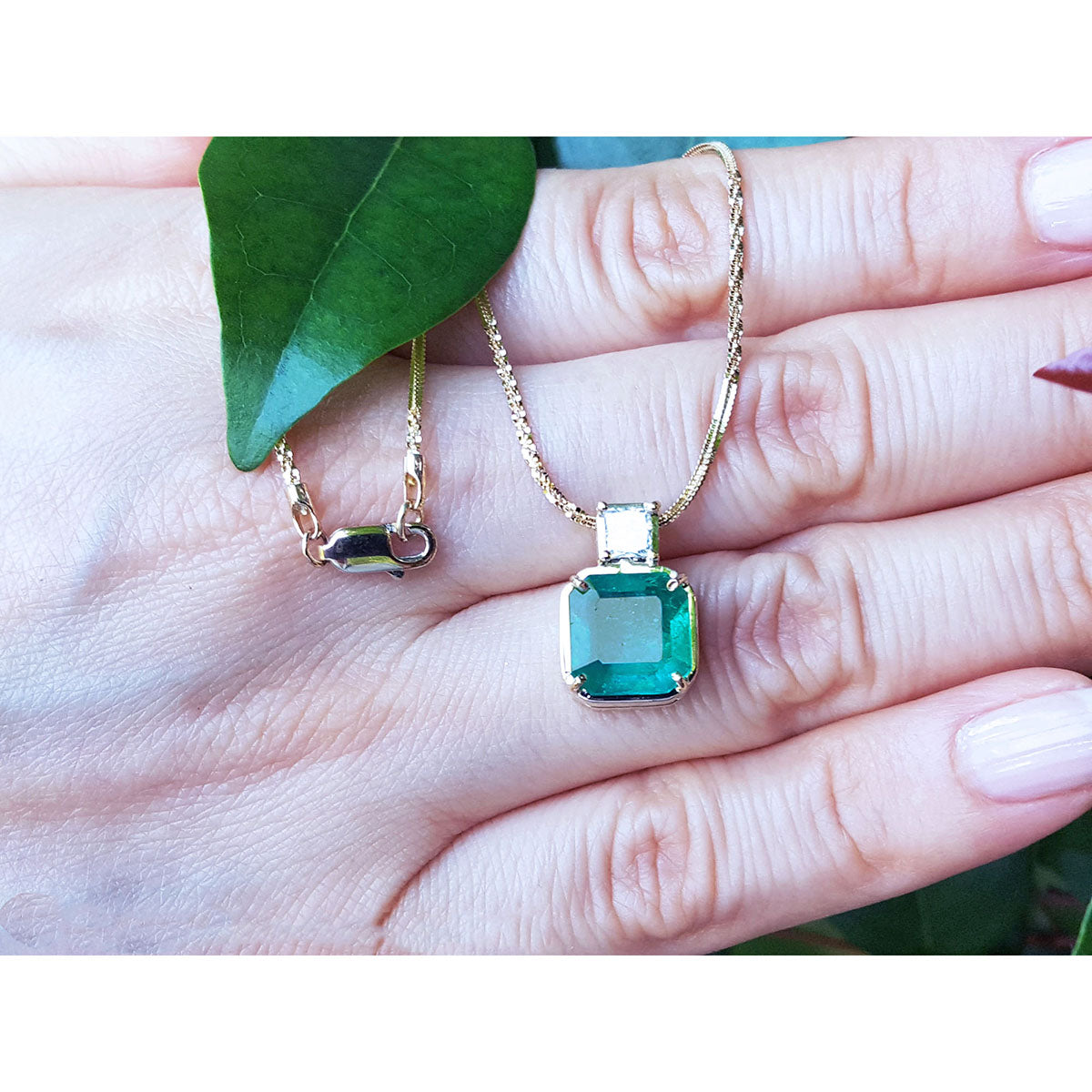 Displaying a natural Asscher cut natural emerald pendant necklace on a woman&#39;s han
