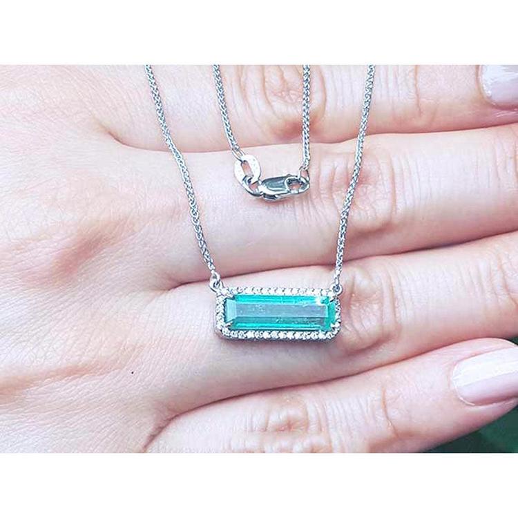 18K white gold necklace with a rectangular emerald-cut Colombian emerald and halo diamonds.
