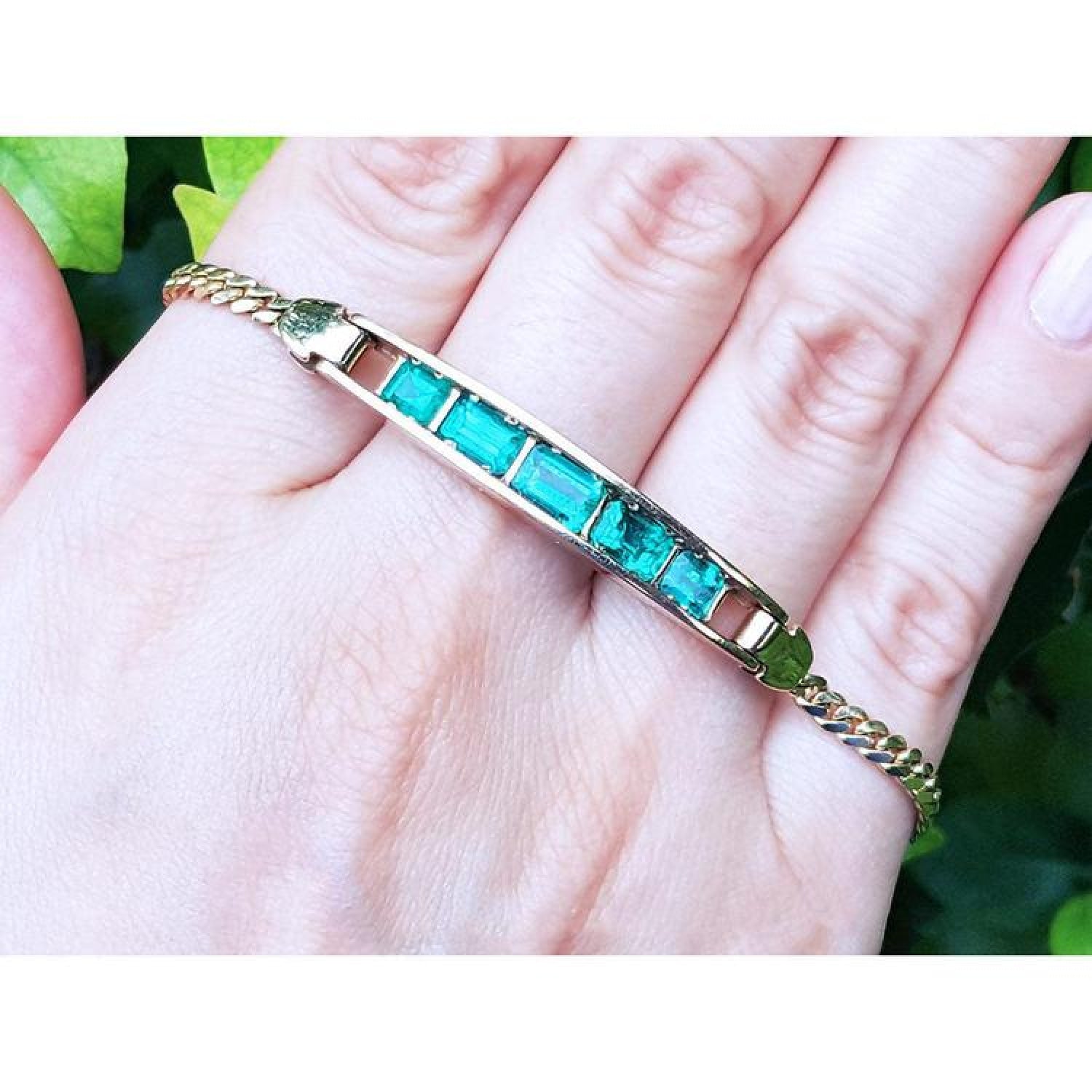 14K yellow gold bracelet with five emerald-cut Colombian emeralds on a woman's hand.