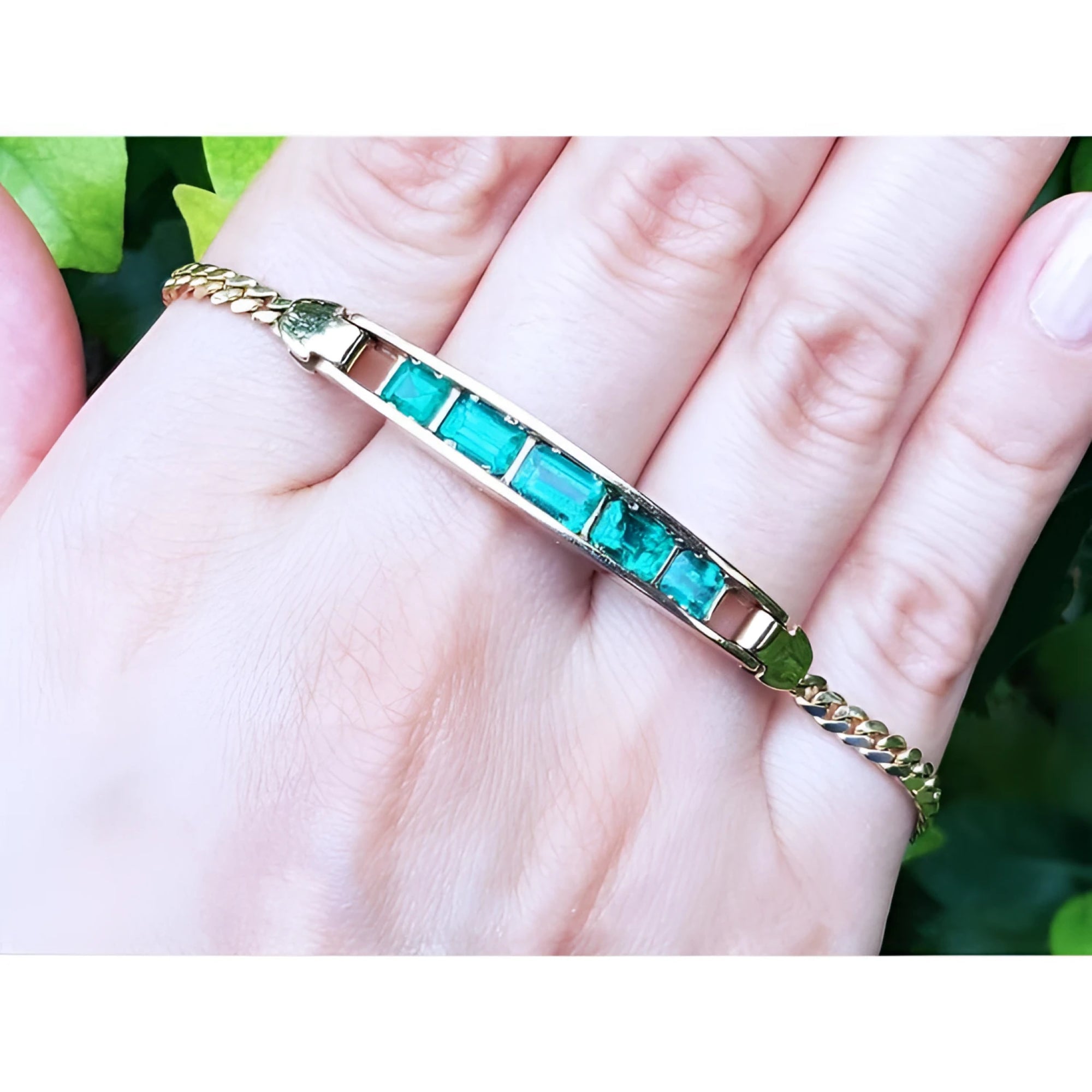 14K yellow gold bracelet with five emerald-cut Colombian emeralds on a woman's hand.