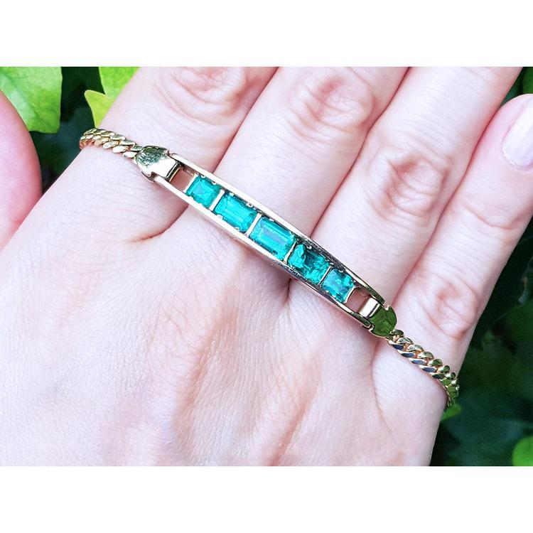 14K yellow gold bracelet with five emerald-cut Colombian emeralds on a woman's hand.