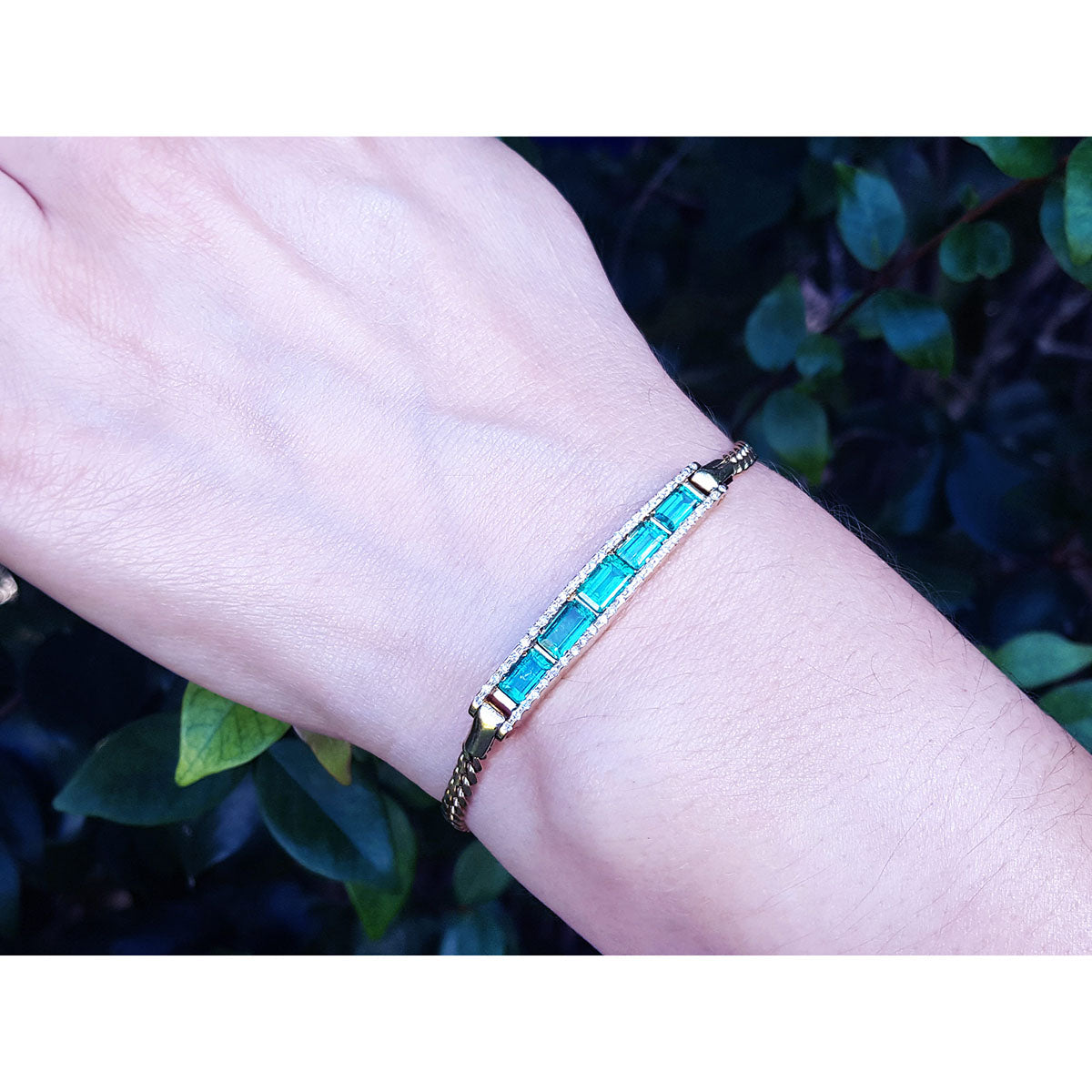 A natural colombian emerald bracelet on a wrist with a natural background.