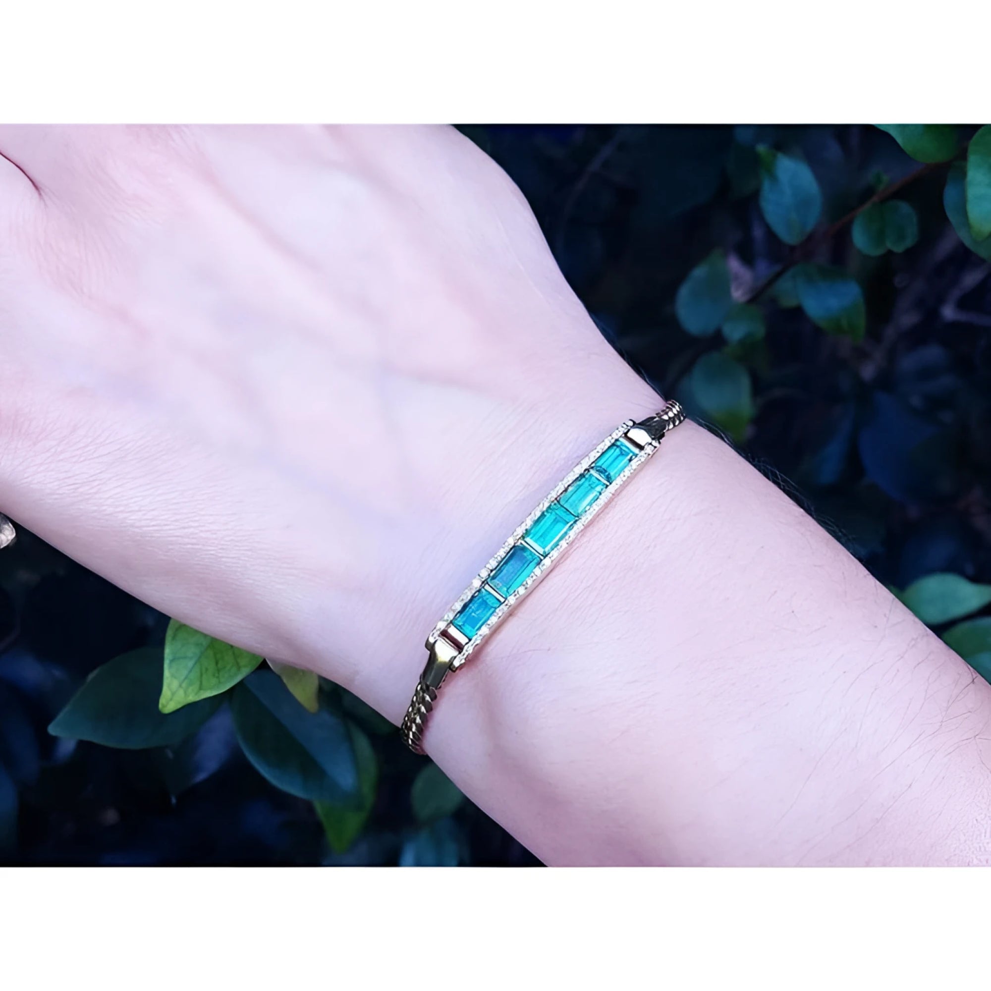 2.40 ct emerald and diamond 14K yellow gold bracelet on a wrist, featuring vibrant bluish-green stones.