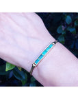 A natural colombian emerald bracelet on a wrist with a natural background.