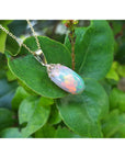 Opal pendant necklace on a gold chain on a green leaf