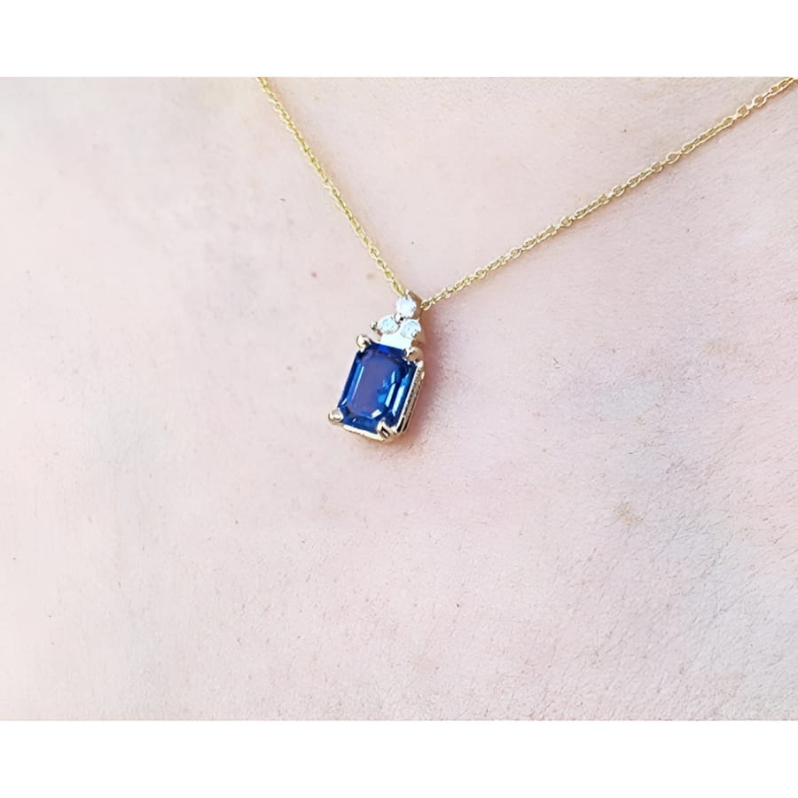 14k gold necklace with a rectangular blue sapphire pendant and three accent diamonds.