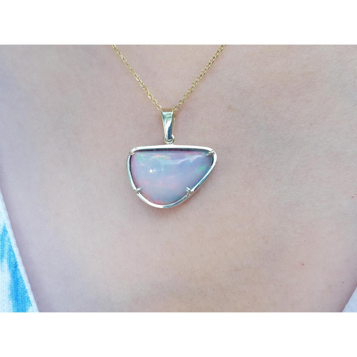 Opal pendant necklace on a person's neck with a plain background