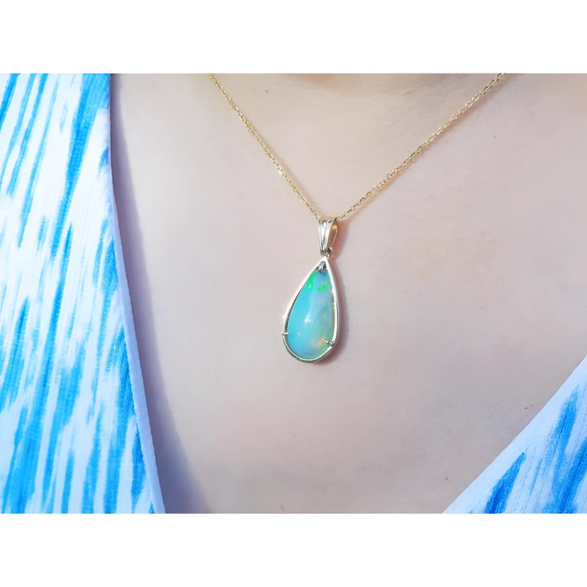 Pear-shaped Ethiopian opal pendant with blue-violet play-of-color in 14K yellow gold on a woman's neck.