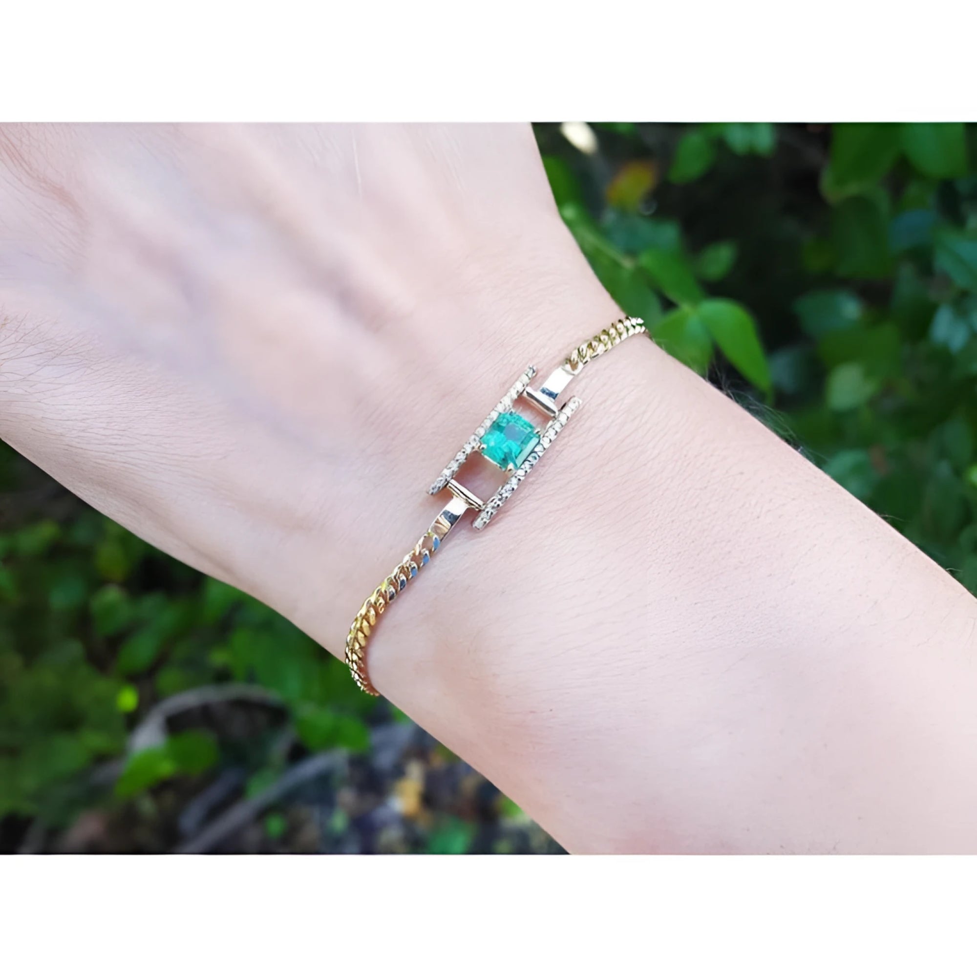 14K yellow gold bracelet with a central emerald-cut Colombian emerald flanked by diamond rows.