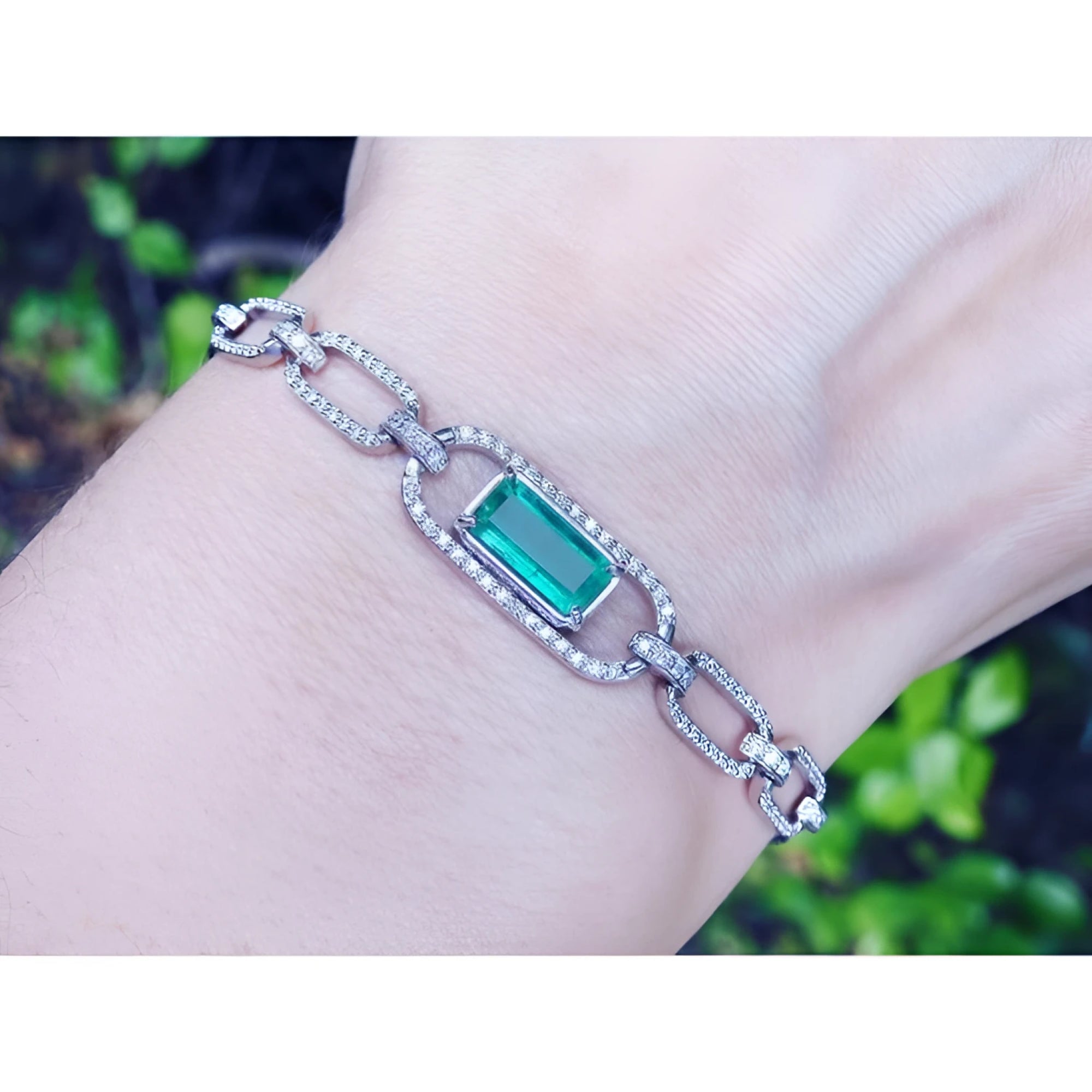 14K white gold paperclip bracelet with a vibrant emerald-cut emerald and diamond halo.