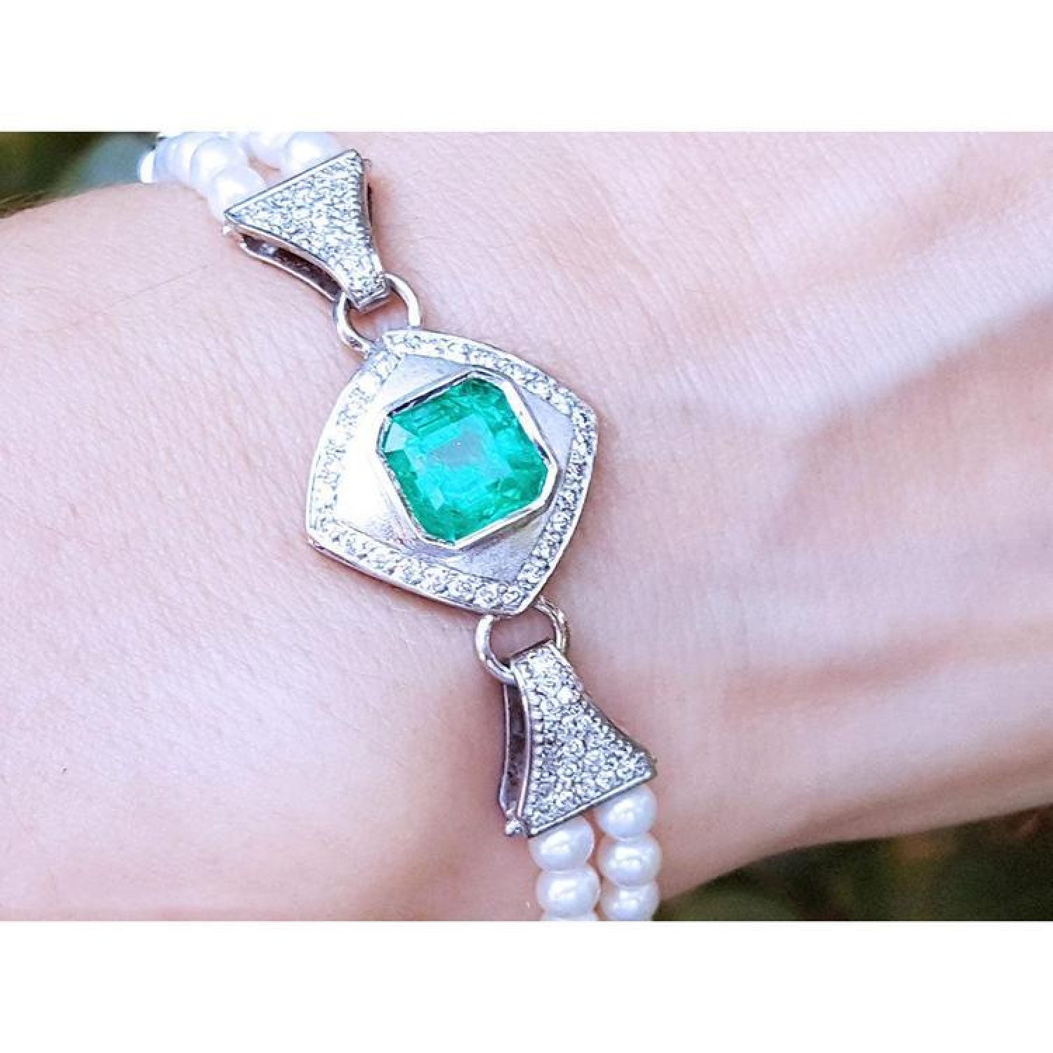 18K white gold emerald and pearl bracelet with a bezel-set green emerald, diamonds, and two strands of pearls.