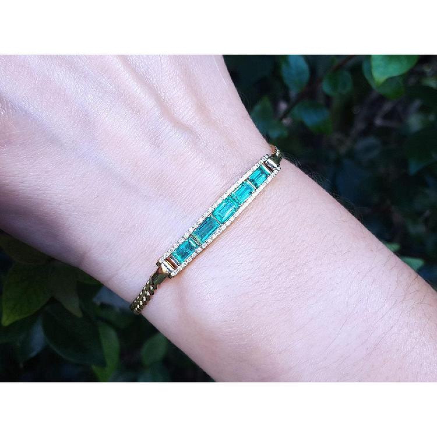 2.40 ct. Colombian emerald and diamond 14K yellow gold bracelet on a wrist.