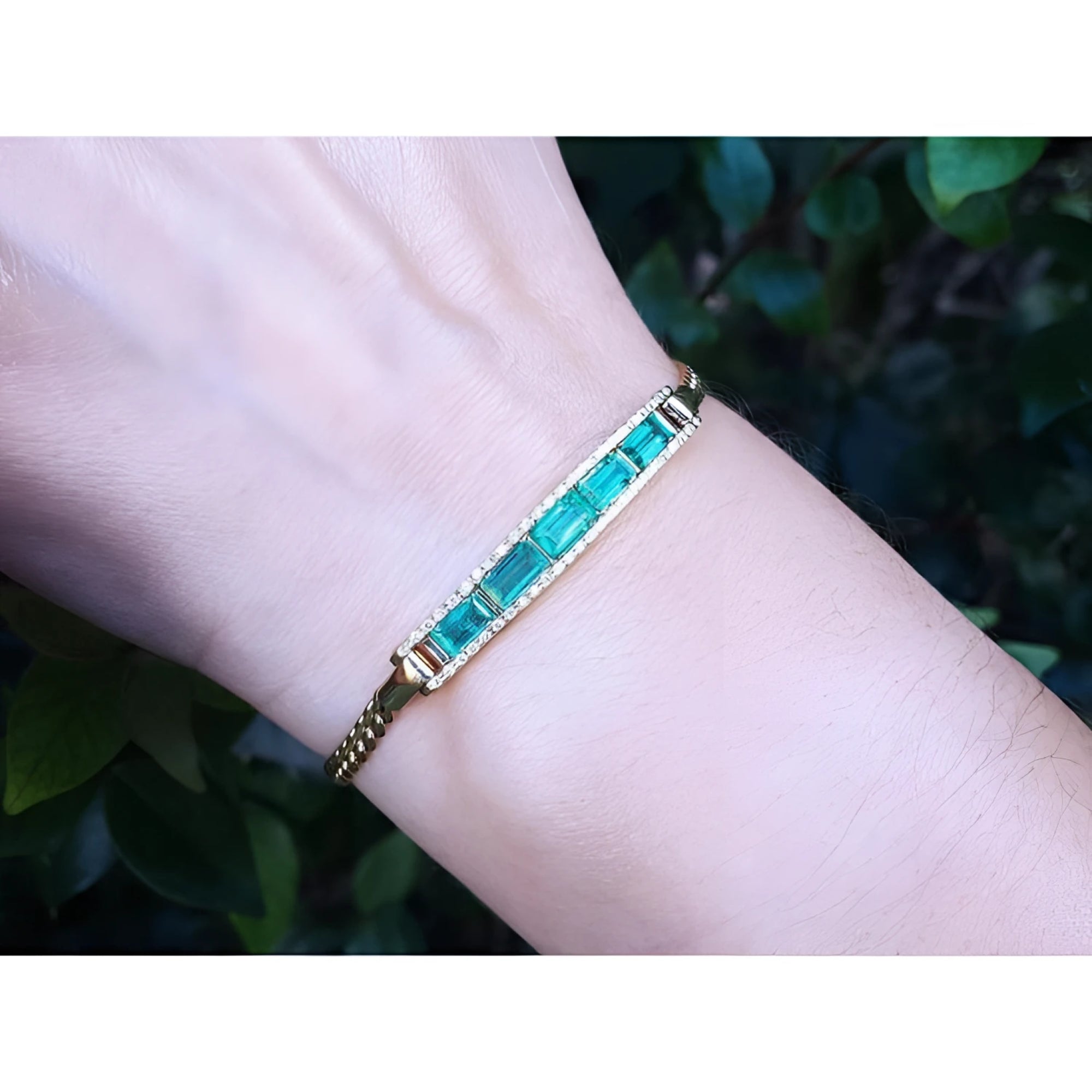 2.40 ct. Colombian emerald and diamond 14K yellow gold bracelet on a wrist.