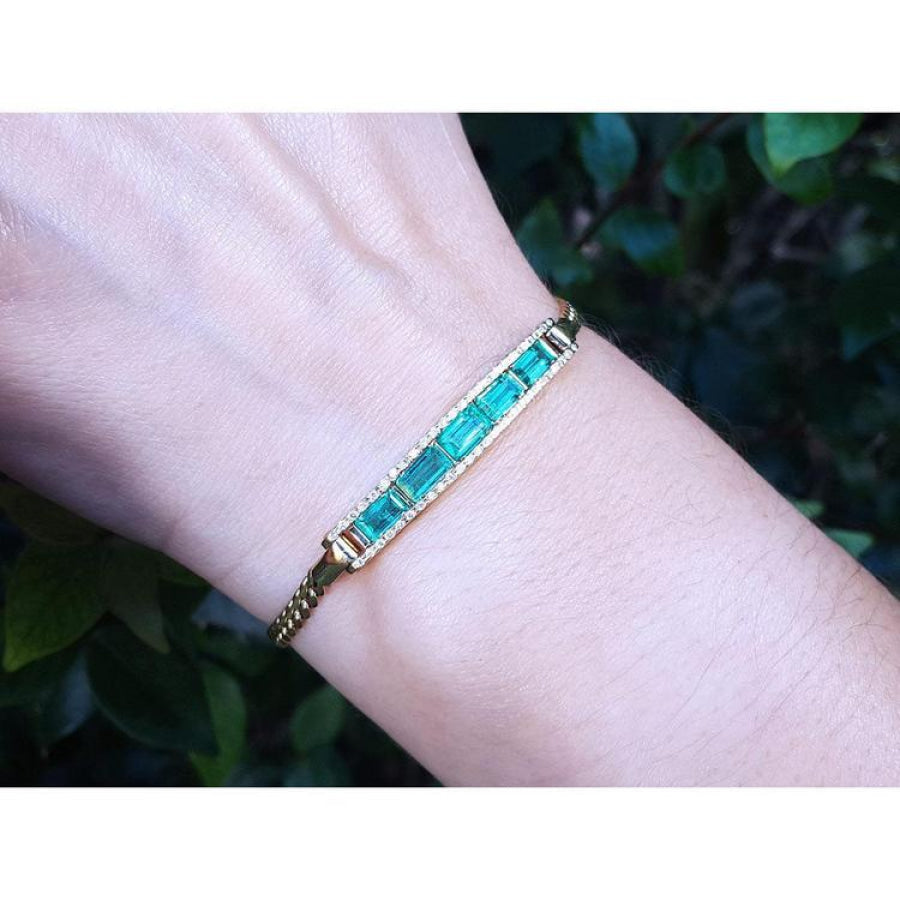 2.40 ct. Colombian emerald and diamond 14K yellow gold bracelet on a wrist.