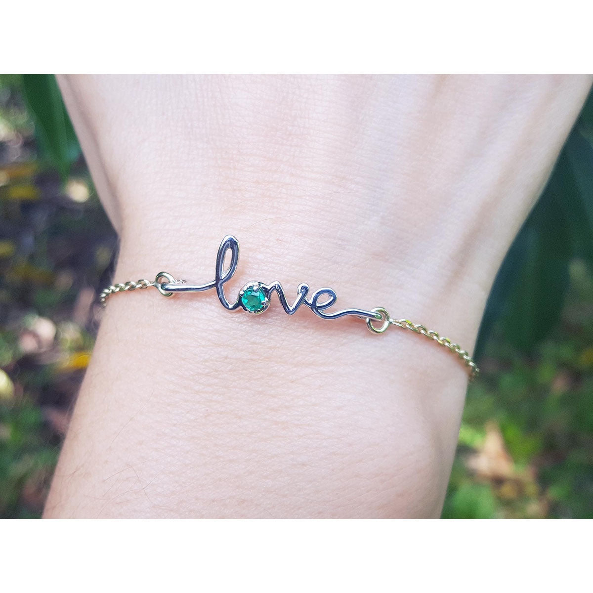 A Love bracelet white and yellow gold with a round cut natural Colombian emerald on a wrist.