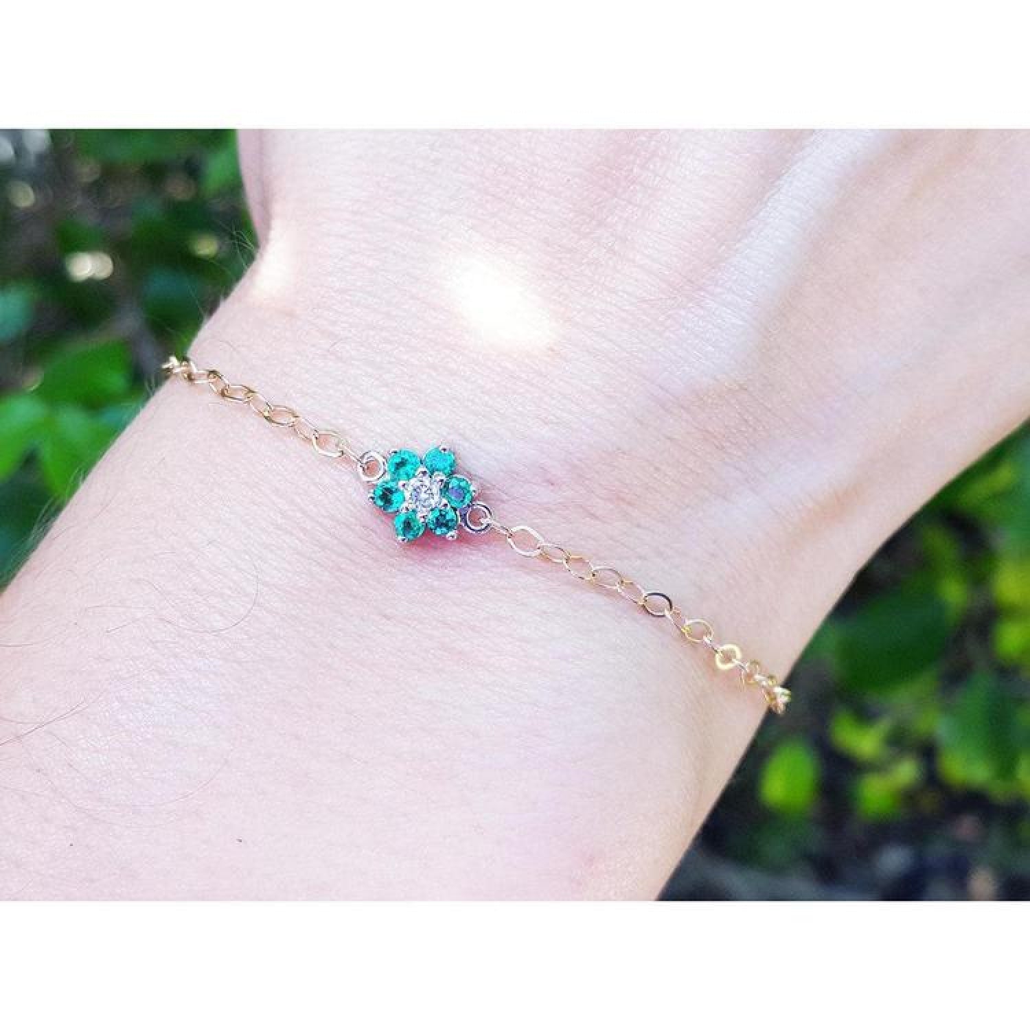 14K yellow gold chain bracelet with a central cluster of six round emeralds and one diamond.