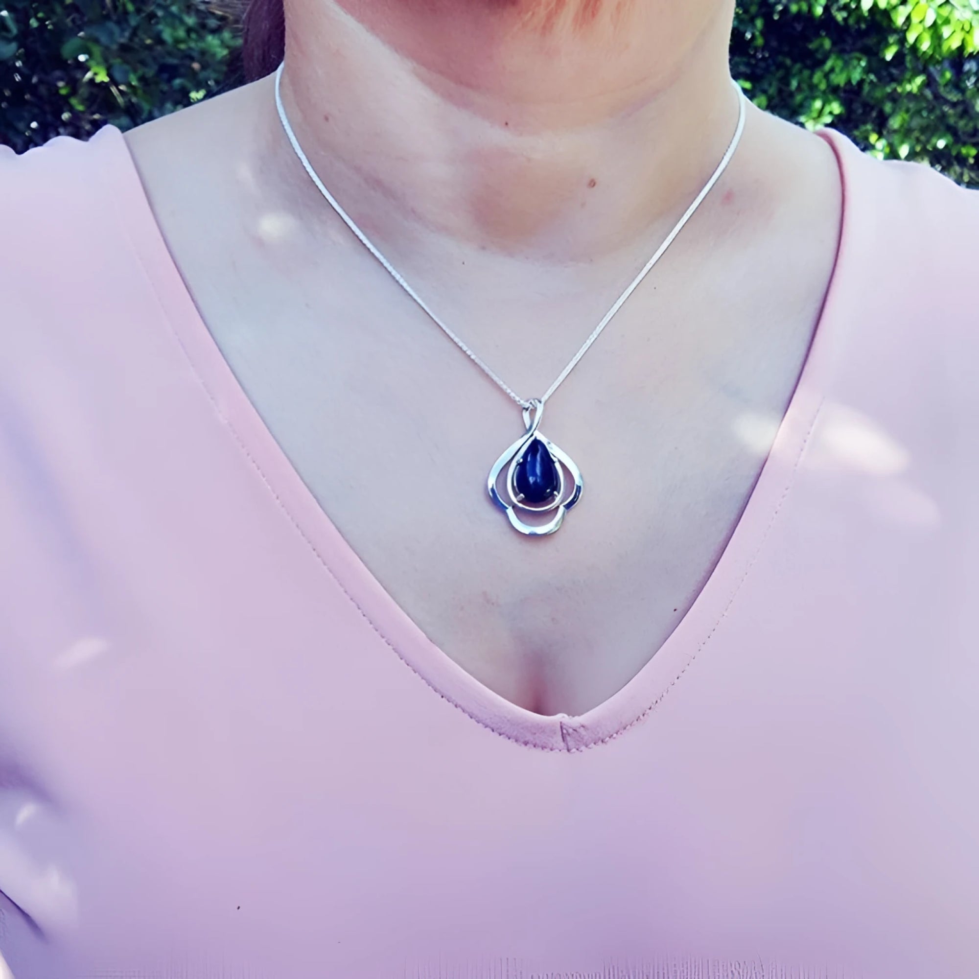 Teardrop 4.30 ct Ethiopian black opal pendant in sterling silver on a woman's neck.