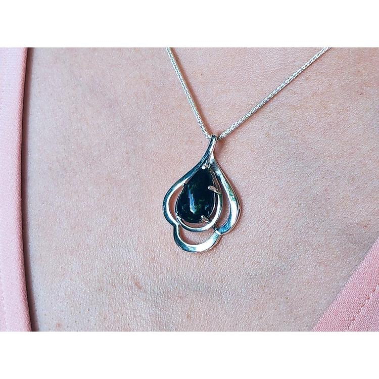 4.30 ct. teardrop Ethiopian black opal pendant in sterling silver, worn on a woman's chest.