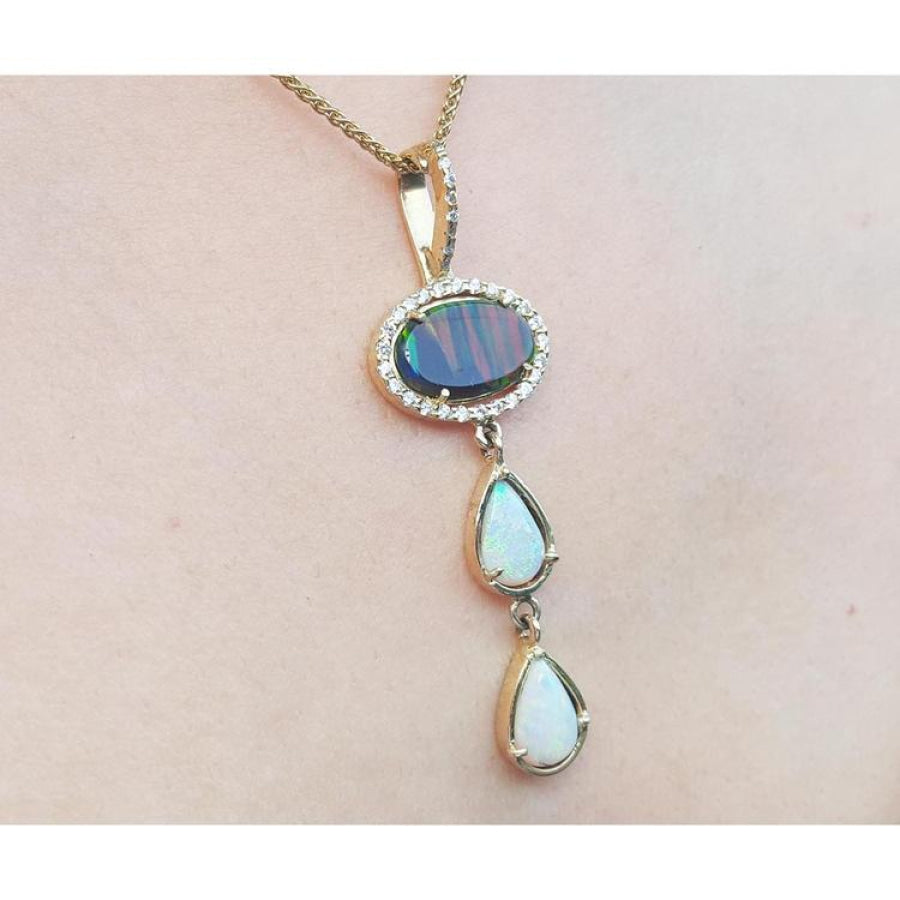 Black and white Australian opal pendant with an oval black opal, two teardrop white opals, and diamond accents on a 14K gold chain.