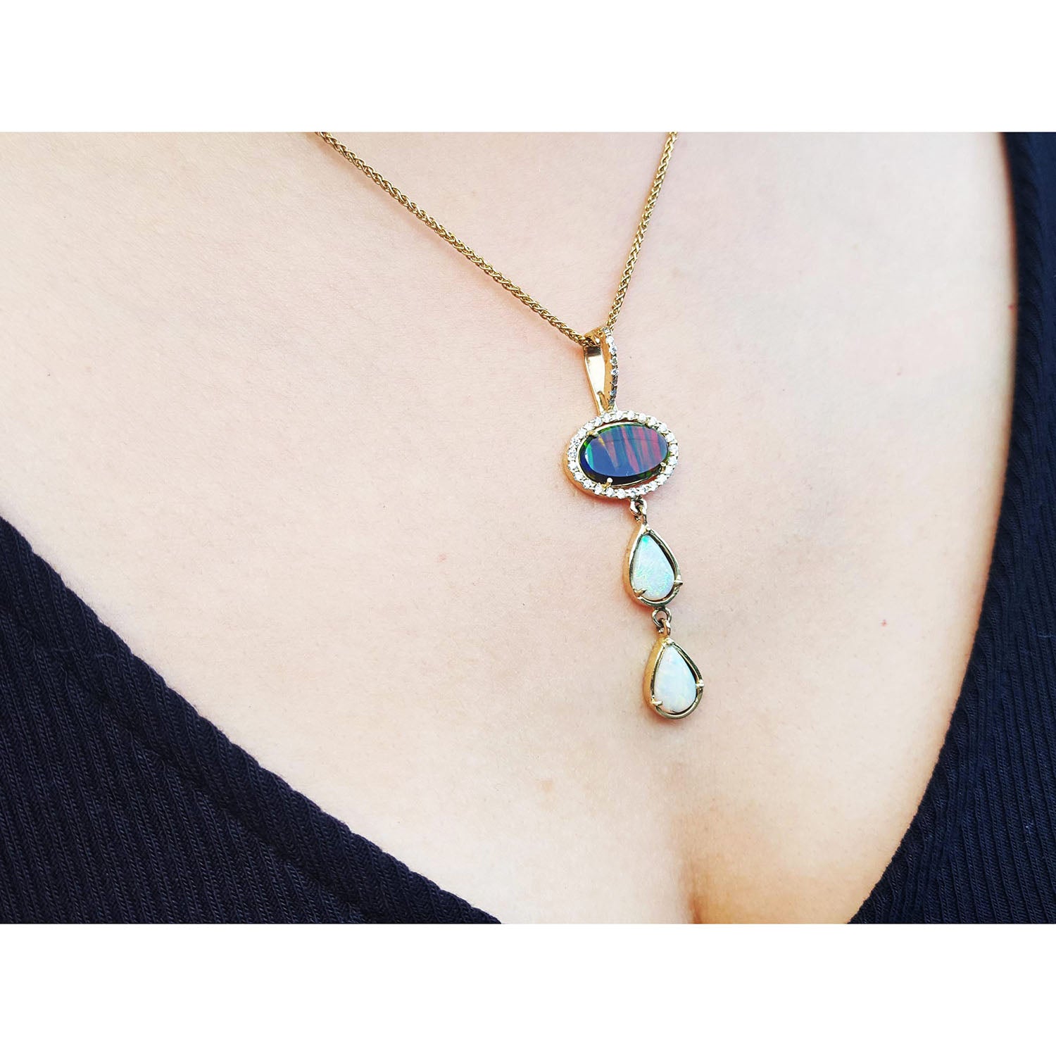 Necklace with opal pendant on a person wearing a black top.