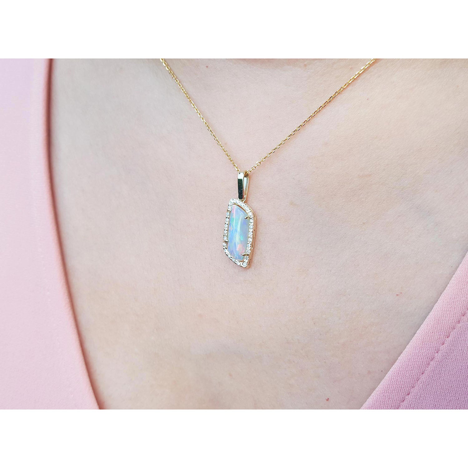 Gold necklace with a natural opal pendant on a person&#39;s neck wearing a pink top.