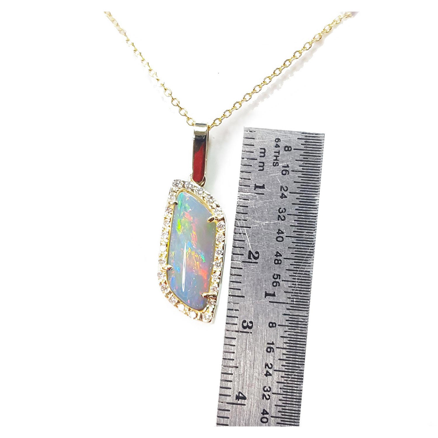 Opal pendant necklace with a ruler for scale on a white background