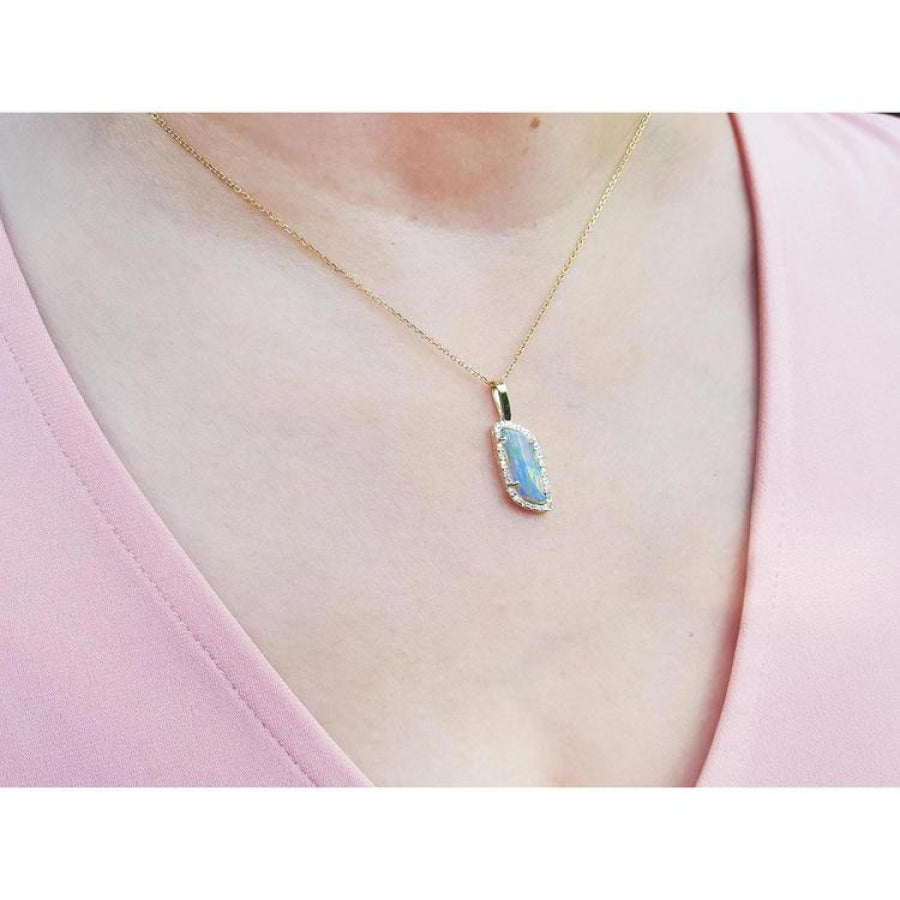 14K yellow gold necklace with a vibrant opal and diamond pendant on a woman's chest.