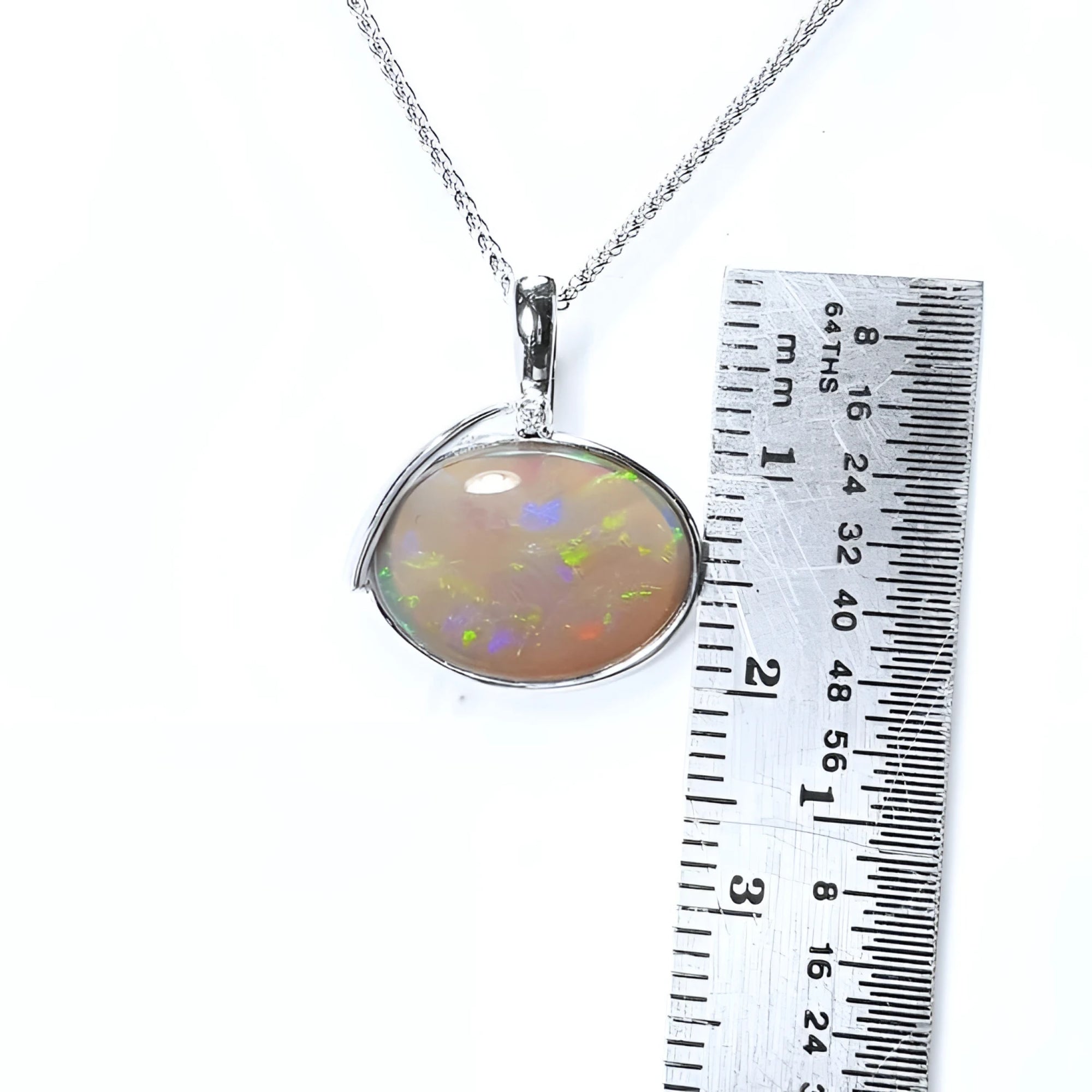 2.25 ct. Australian opal pendant in 14K white gold with bluish-green flashes, shown with a ruler.