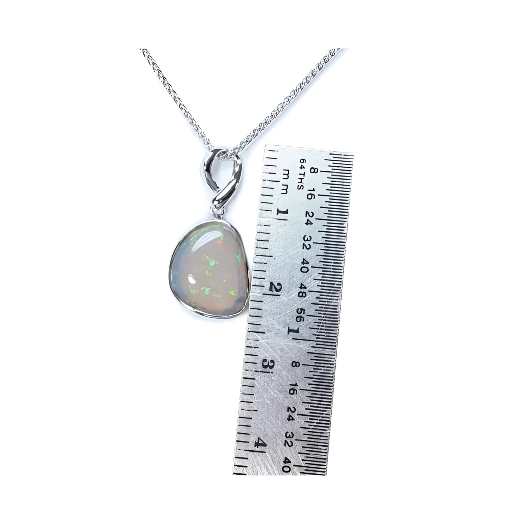 Freeform bluish-green Australian opal pendant, bezel set in 14K white gold, shown with a ruler for scale.