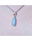 Necklace with a light blue pendant on a person's neck