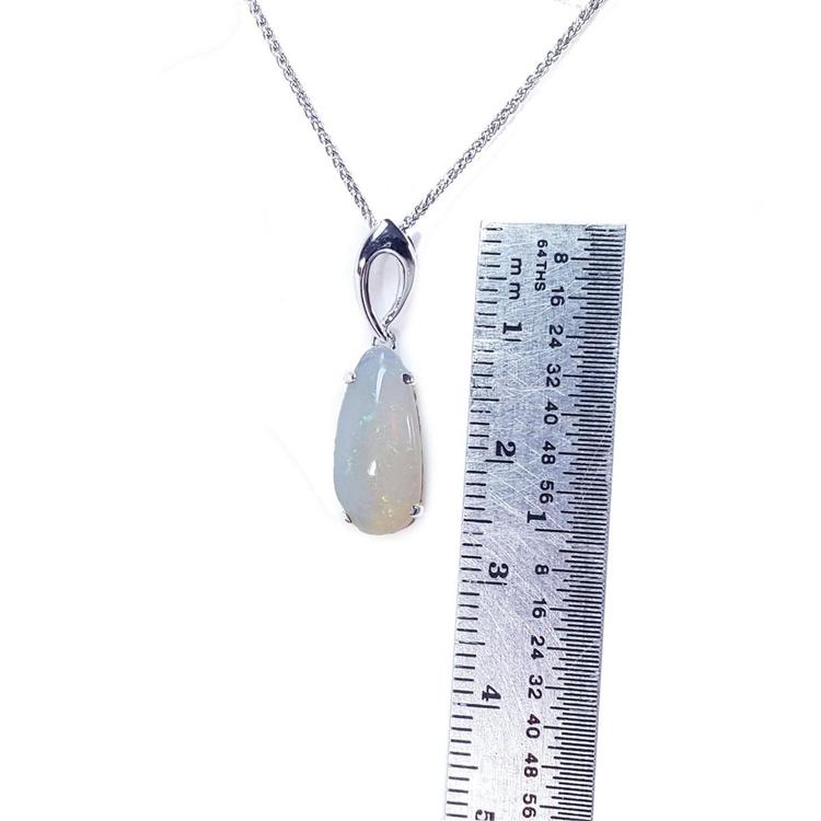 Necklace with an opal pendant next to a ruler on a white background