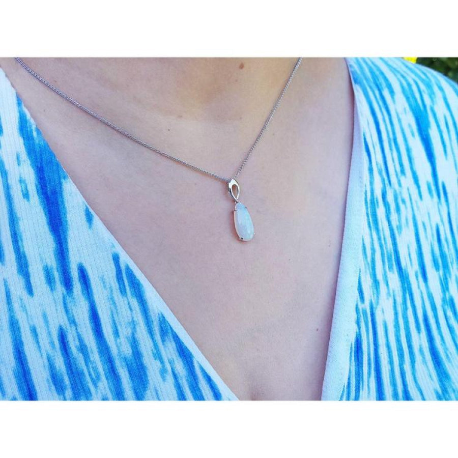 Pear-shaped white opal solitaire pendant in 14K white gold on a silver chain, worn on a person.